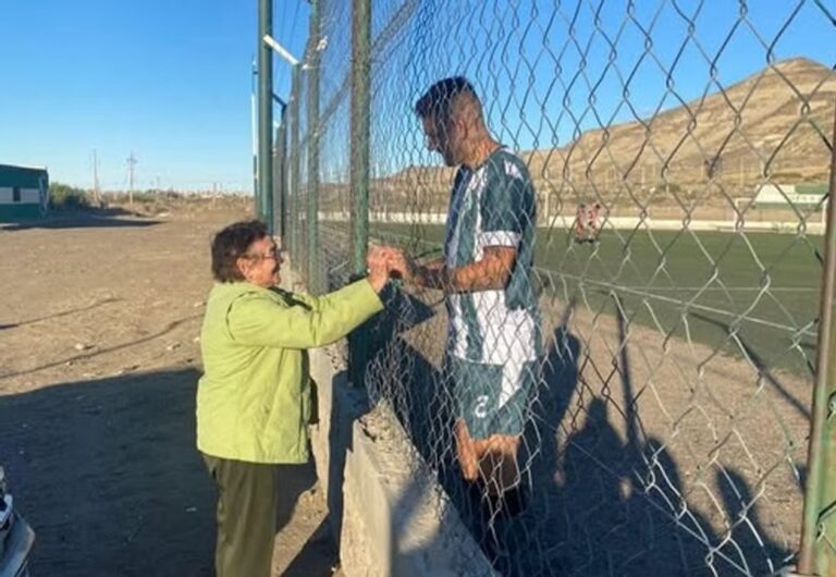 Celia, bisabuela de 89 años, saluda a su bisnieto Agustín Herrera a través del alambrado en la cancha de Laprida, Comodoro Rivadavia.
