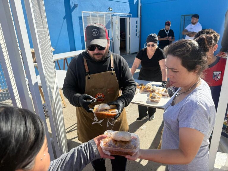 Personas participando en la olla popular y recibiendo alimentos en la sede vecinal del barrio Quirno Costa, Comodoro Rivadavia.