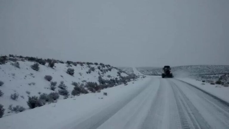 Vista de una ruta patagónica cubierta de nieve con cartel de alerta meteorológica