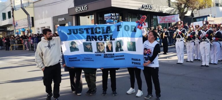 Familiares de Ángel López con bandera y carteles durante desfile del 25 de Mayo en Comodoro Rivadavia