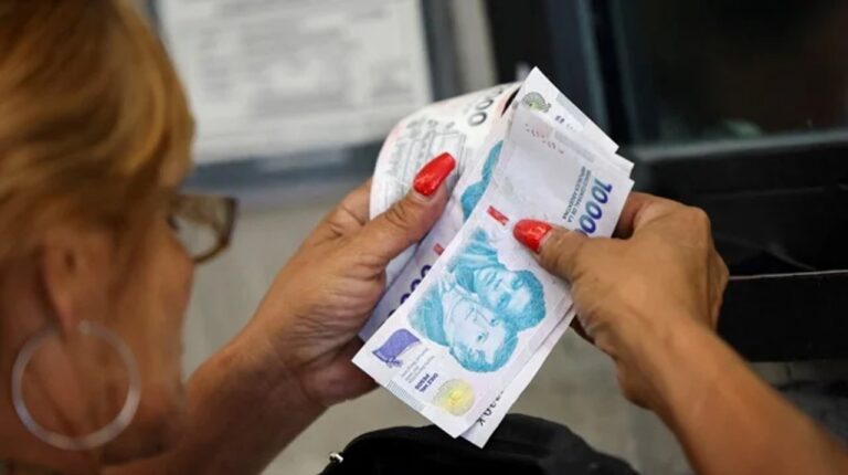 Facturas de servicios y billetes de pesos argentinos sobre una mesa