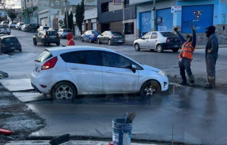 Auto Ford Fiesta blanco atrapado en asfalto fresco de obra de bacheo en Comodoro Rivadavia
