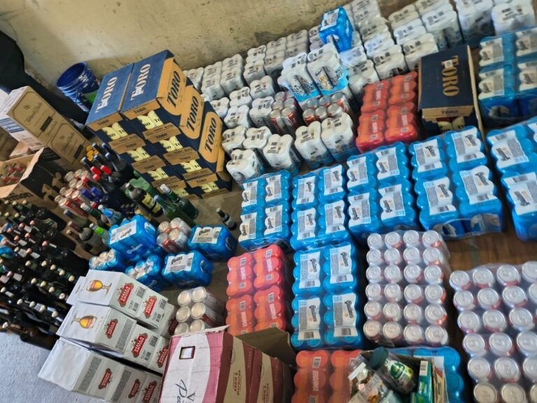 Fotografía ilustrativa de un allanamiento policial con cajas de bebidas alcohólicas secuestradas