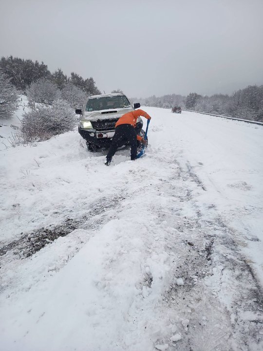 Vista de una ruta nevada en la cordillera de Río Negro, con autos circulando con precaución