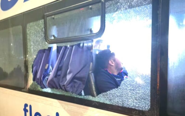 Ventanilla de micro astillada por disparo con manchas de sangre en el pasillo