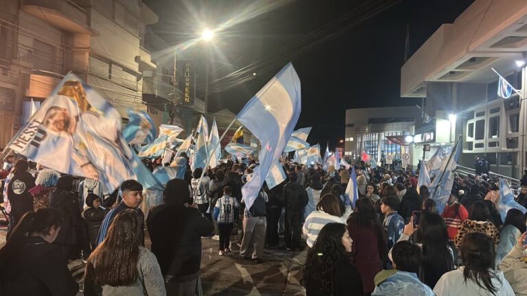 Multitud de hinchas argentinos reunidos en la esquina del Banco Nación en Comodoro Rivadavia con banderas y camisetas