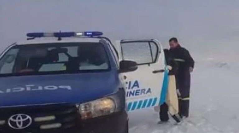 Mujer y niña siendo asistidas por personal policial en un camino nevado